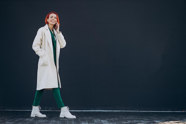 Woman in coat using phone outside the street