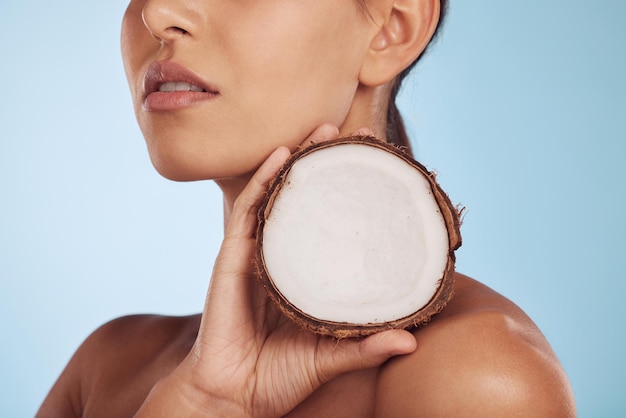 Woman coconut fruit and beauty skincare or vegan cream isolated studio blue background Model or person hands with natural product for dermatology eco friendly cosmetics and oil benefits