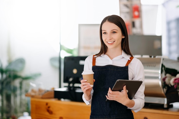 Woman coffee shop owner holding notepad and digital tablet ready to receive orders in cafe restaurant woman barista cafe xA