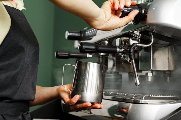 Woman coffee shop worker preparing coffee on professional coffee machine