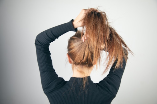 Woman collecting hair in a ponytail in back