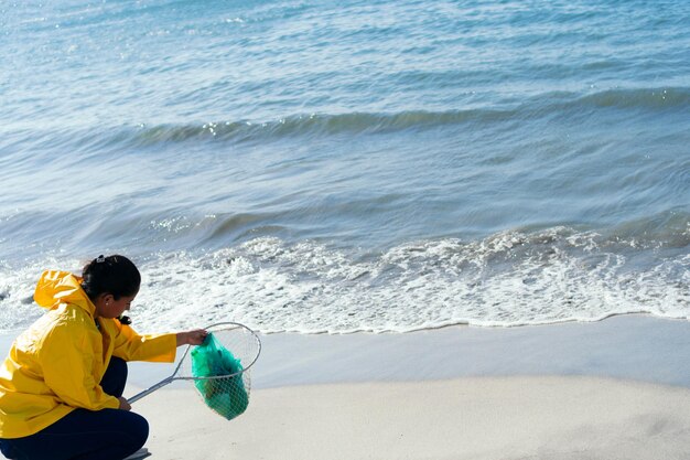 写真 晴れた日にプラスチックごみを収集する女性