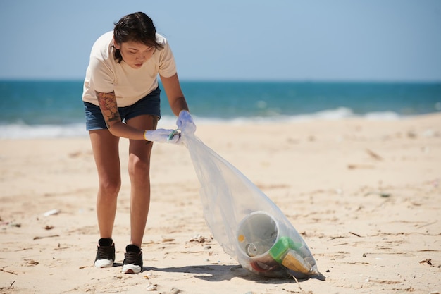 해변에서 쓰레기를 수집하는 여자