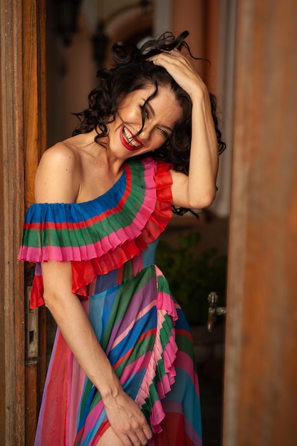 A woman in a colorful dress stands in a doorway.