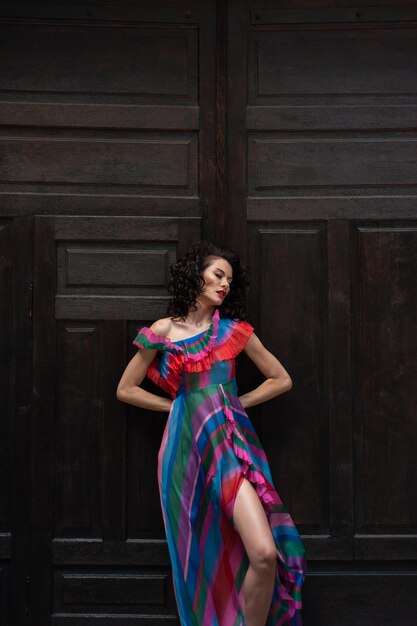 A woman in a colorful dress stands in front of a large wooden door