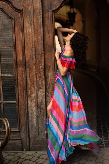 Photo a woman in a colorful striped dress is standing on a door.