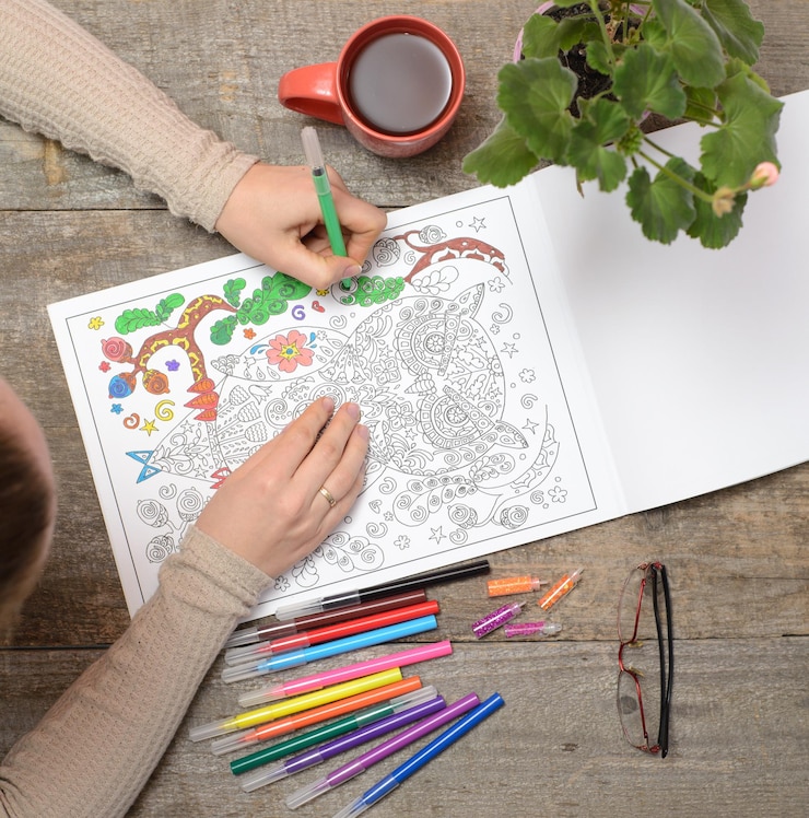 Photo woman coloring an adult coloring book and drinking tea new stress relieving trend mindfulness concept married woman top view