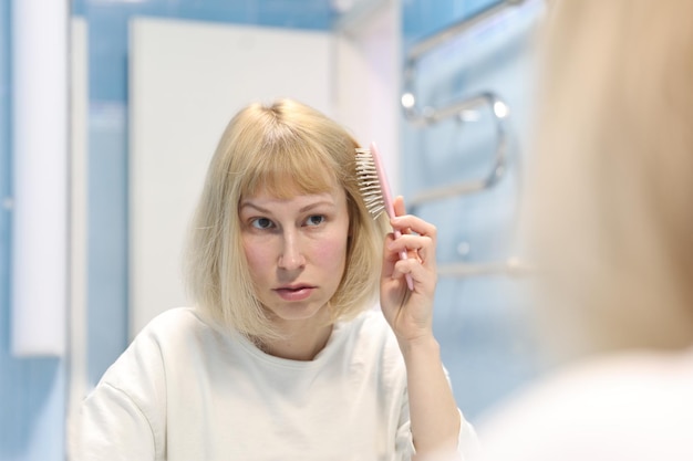 A woman combs her hair in the bathroom