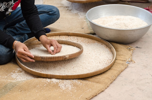 Foto donna competitivo vagliatura di riso utilizzando basketwork di bambù all'aperto