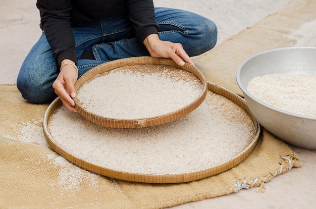 woman competitive winnowing rice by using bamboo basketwork outdoor