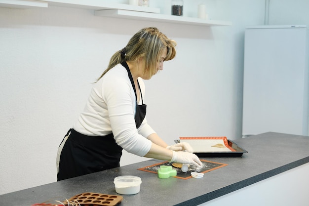 A woman confectioner in white gloves rolls out the dough on a\
baking mat for making gingerbread horizontal photo