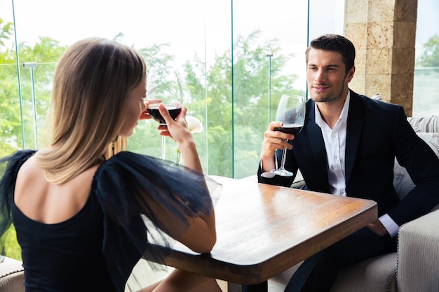 Woman and confident man drinking red wine in restaurant