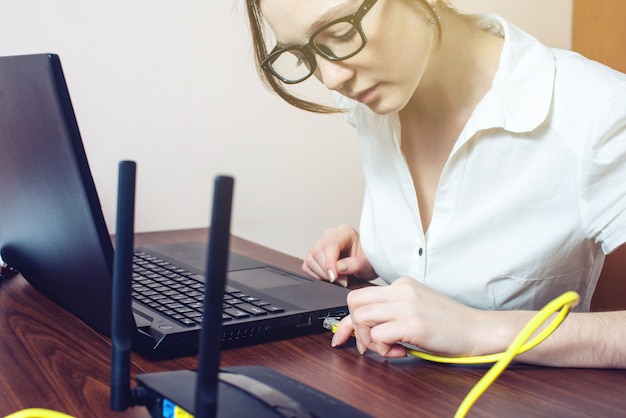 Woman connecting Internet cable to connector on the laptop