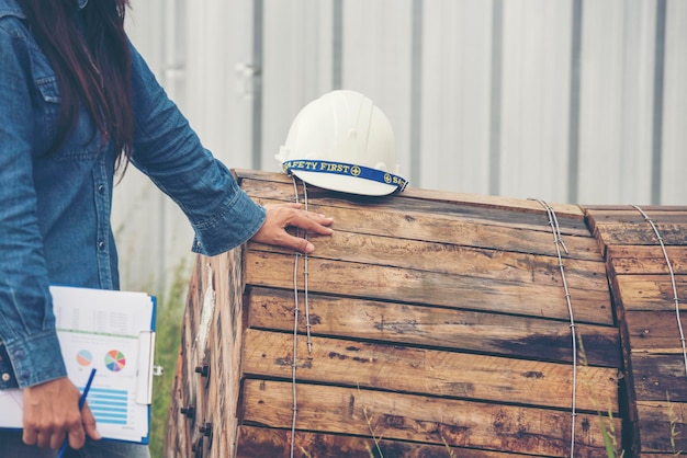 女性の建設エンジニアは、建設現場の産業労働者で安全な白いヘルメットを着用します女性のエンジニア労働者は、ヘルメットの安全ヘルメットを備えた土木工学女性の建設エンジニアのコンセプト