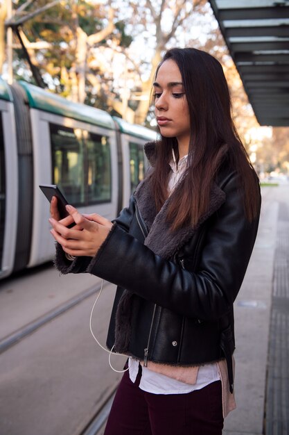 Woman consulting telephone at the streetcar stop