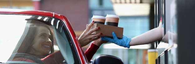 Woman in convertible car picks up tea and coffee