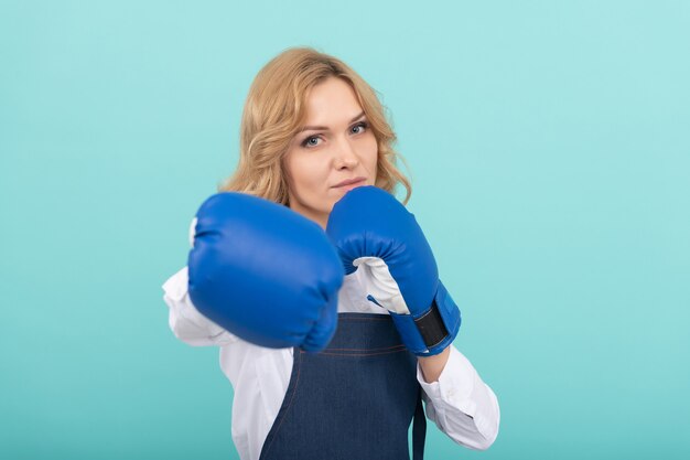 Woman in cook apron punching boxing gloves, boxer.