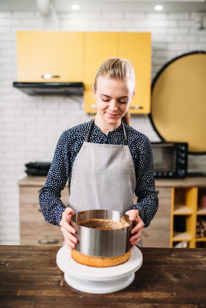 Woman cook in apron takes the form of a baked cake.