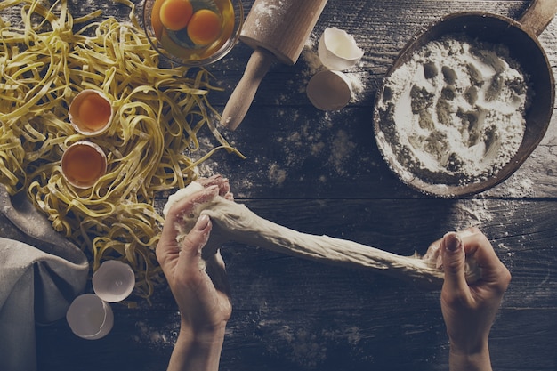 Woman cook hands preparing making tasty homemade classic italian pasta on wooden table. Closeup. Top View. Toning.