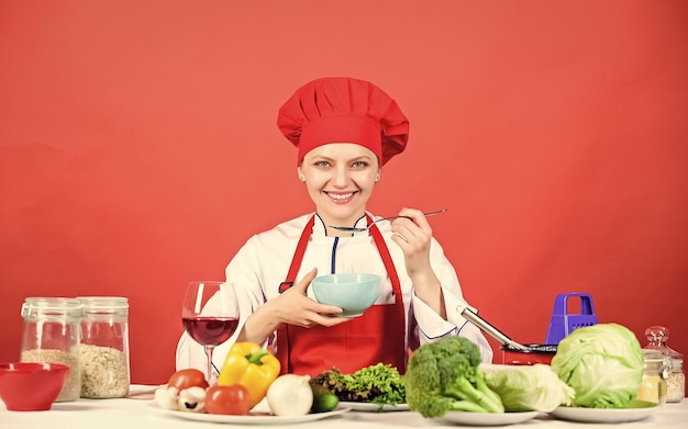 Woman in cook hat professional chef on red background happy woman cooking healthy food by recipe organic eating and vegetarian Housewife restaurant menu Dieting Who cares about diet