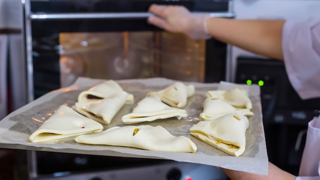 Woman cook lays cheese puffs on baking sheet in oven.