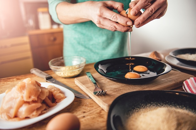 女性の料理と卵を皿に割る