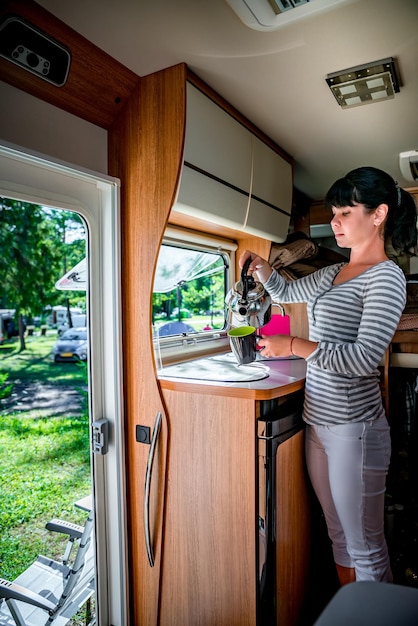 Woman cooking in camper, motorhome interior. Family vacation travel, holiday trip in motorhome RV, Caravan car Vacation.