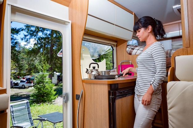 Woman cooking in camper, motorhome RV interior. Family vacation travel, holiday trip in motorhome, Caravan car Vacation.