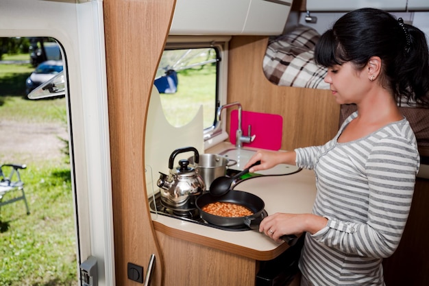 Foto donna che cucina in camper, interni camper. viaggio di vacanza in famiglia, viaggio di vacanza in camper, vacanza in caravan.