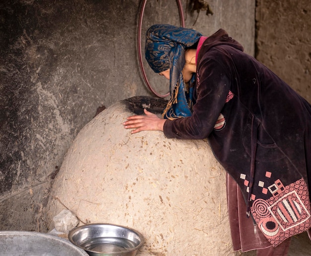 Woman cooking in a clay oven