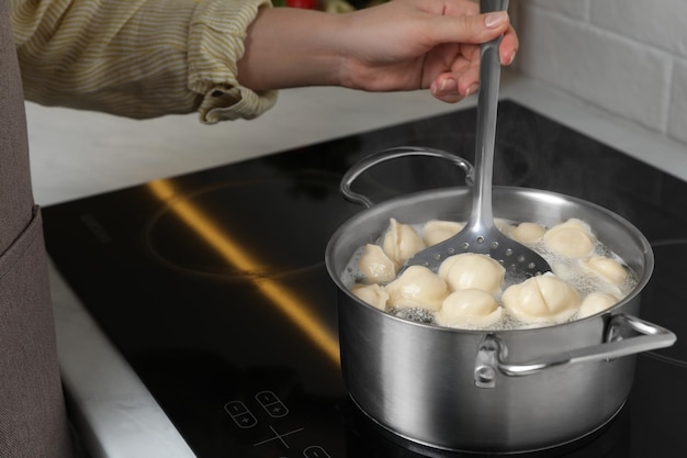 Foto donna che cucina gnocchi in casseruola con acqua bollente sul primo piano del piano di cottura