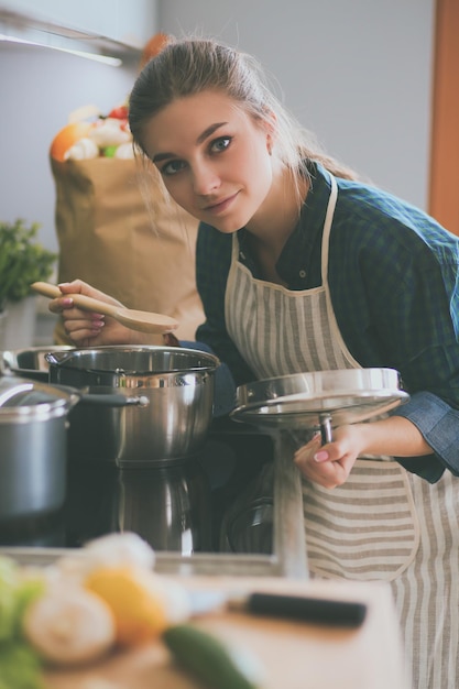 A woman cooking in a kitchen with a bag of food on the counter.