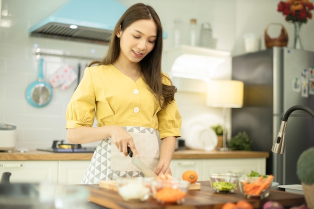 キッチンで野菜とご飯を炊く女性