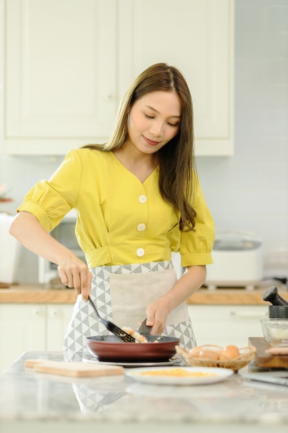 Woman cooking rice with vegetables in kitchen