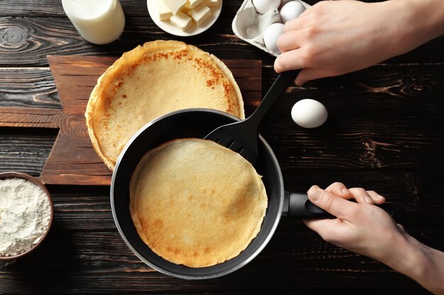 Woman cooking Russian pancakes in kitchen closeup