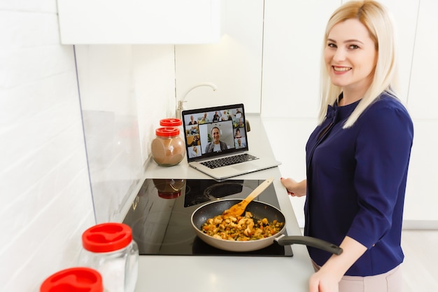 Foto una donna che cucina e usa il laptop in cucina