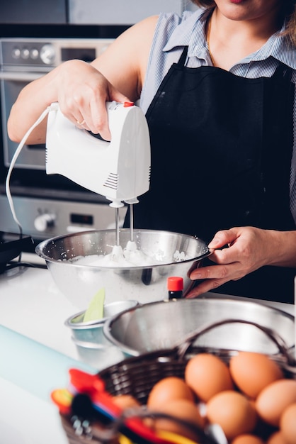 Woman cooking whisk dough mixer in bowl by machine