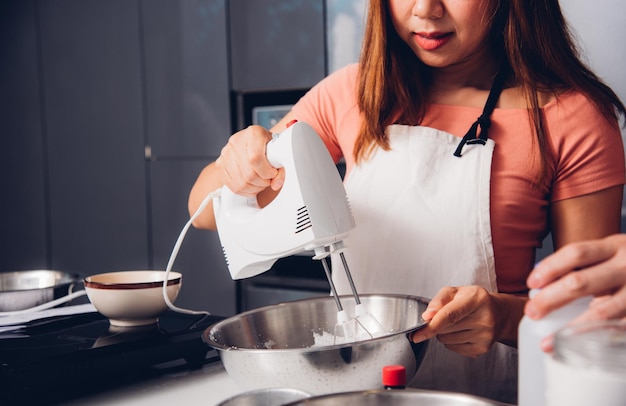 Женщина готовит тесто венчиком в миске