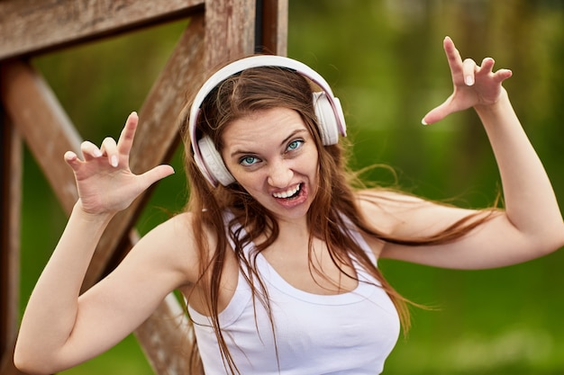 Woman in cordless headphones makes grimace outdoors