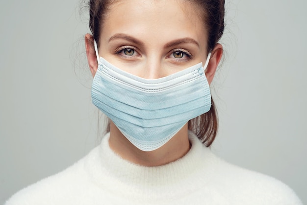Woman and coronavirus disposable mask portrait face of a\
smiling young brunette