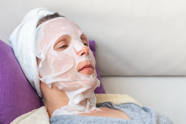 Woman in cosmetic mask lies on sofa close-up