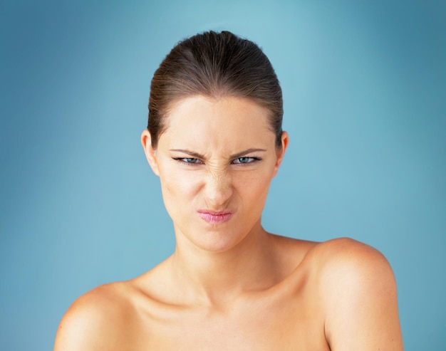 woman cosmetics and beauty in portrait as unhappy with treatment for healthy skin in blue background female person results and face as frustrated fail or crisis for skincare or wellness in studio