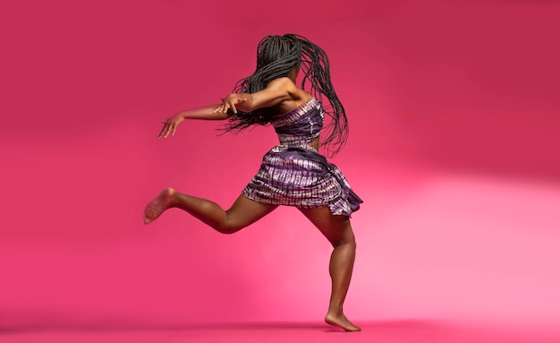Woman in costume dancing against pink background