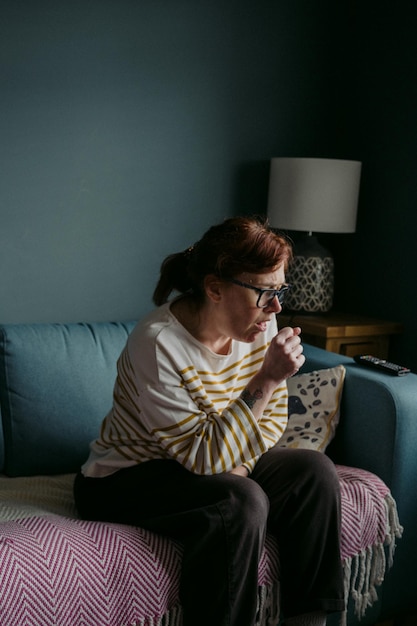 woman coughing while sitting on sofa at home
