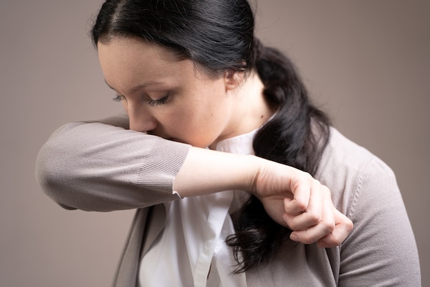 The woman coughs into her elbow. Coronavirus prevention