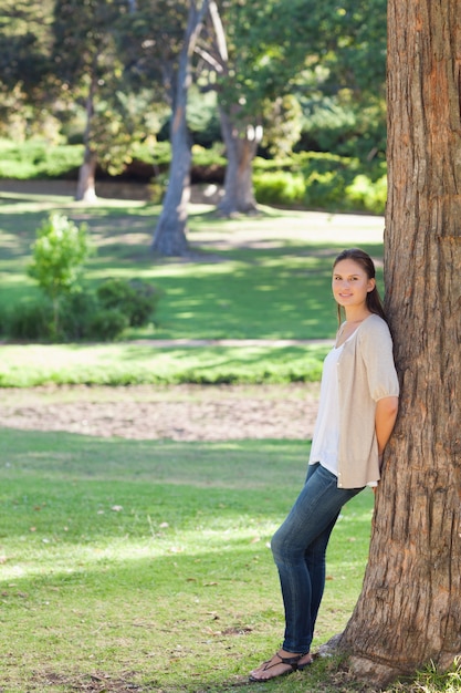 Woman in the countryside leaning against a tree