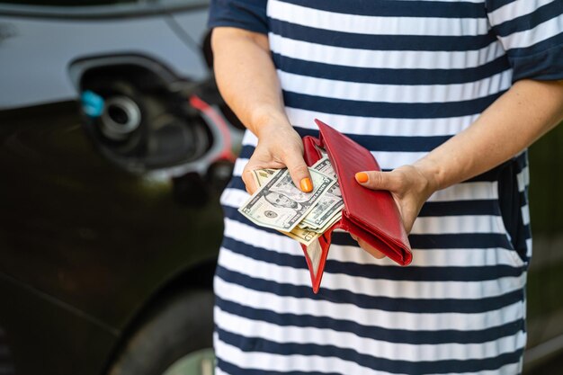 A woman counts money standing at an open fuel tank the concept of rising fuel prices closeup