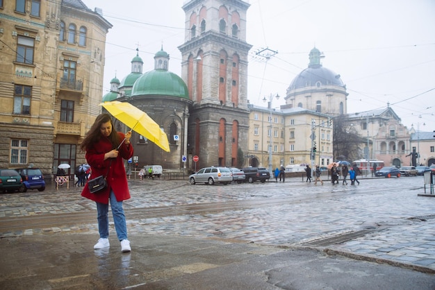 Женщина прикрывается желтым зонтиком в штормовую тревогу в ветреную погоду