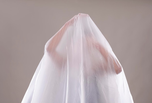 Woman covered in white textile over white background