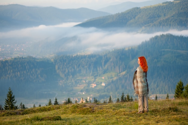 woman covered with a blanket standing on hill
